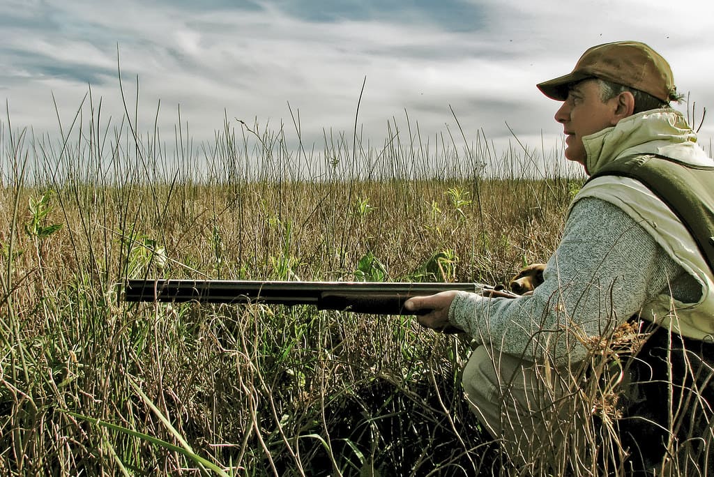 cazador con escopeta oculto entre matorrales