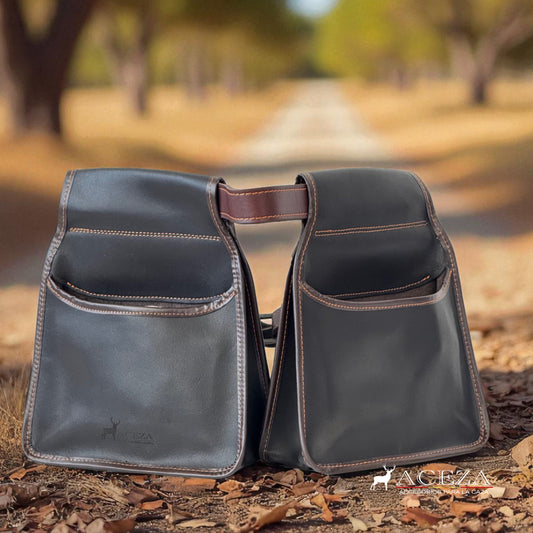 Bolsa de ojeo Aceza en cuero marrón oscuro sobre un camino rural de campo abierto con hojas secas.